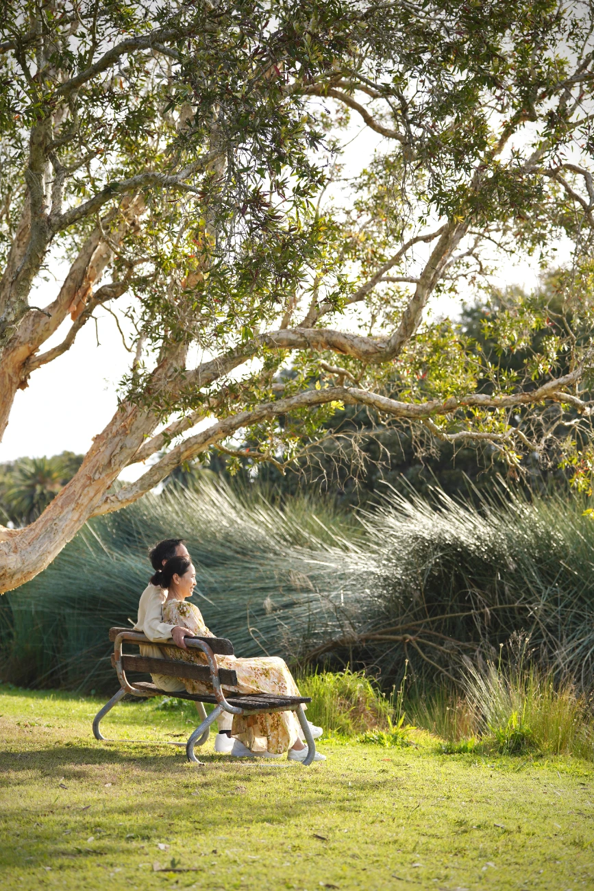 Couple resting beneath a paperbark tree
